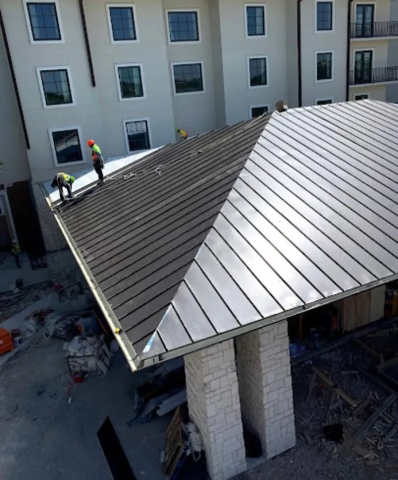 Crew installing standing seam metal roof panels on a commercial project in Lockhart